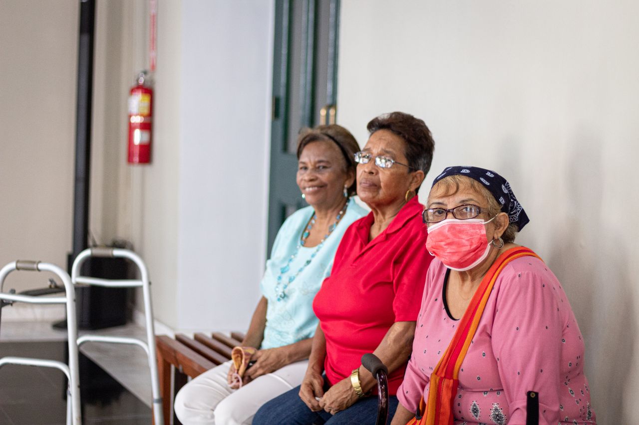 Mastering the First Impression: Your intriguing post title goes here Three senior women sitting indoors, one wearing a face mask, in a safe environment.