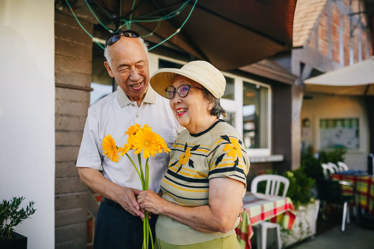 The Art of Drawing Readers In: Your attractive post title goes here Happy senior couple enjoying a moment with yellow flowers outside a restaurant.